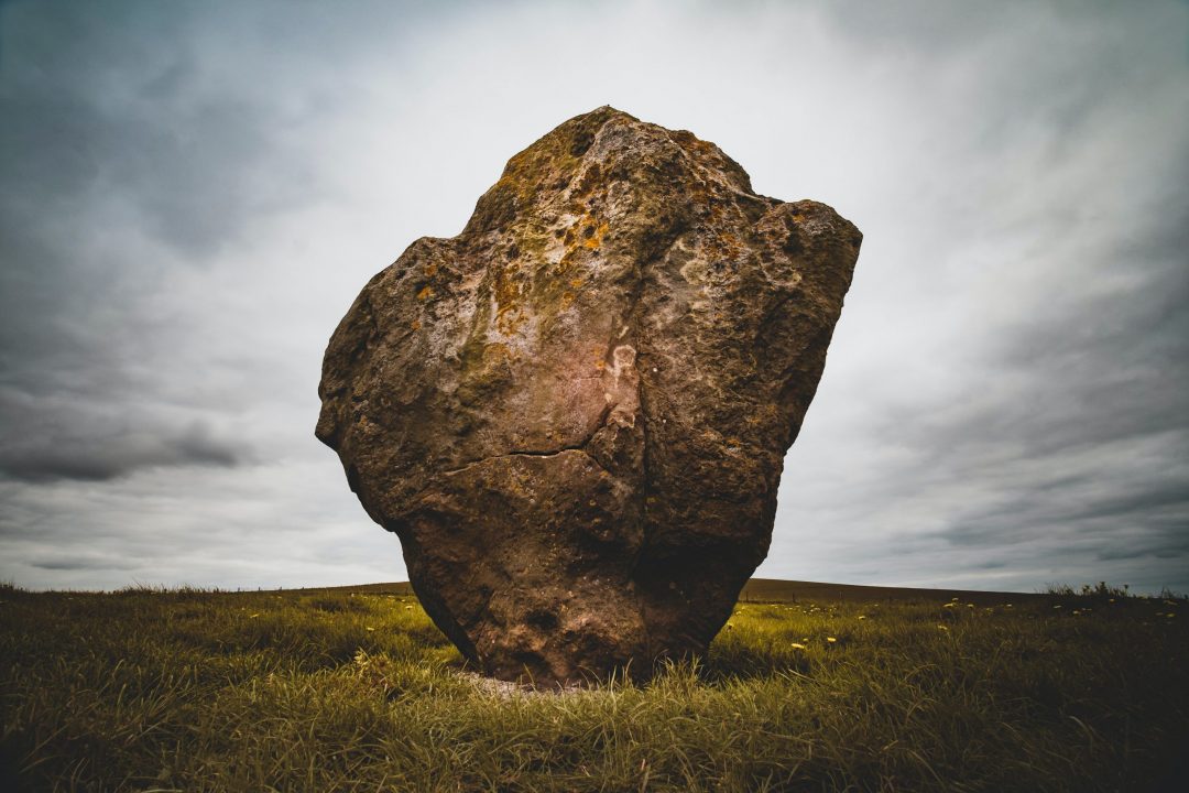 brown rock formation surrounded by green grass