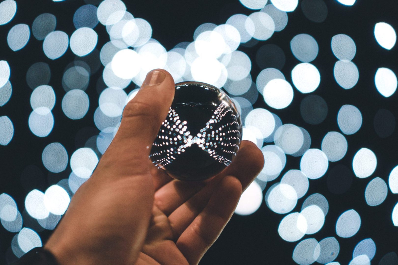 person holding silver ball with bokeh background